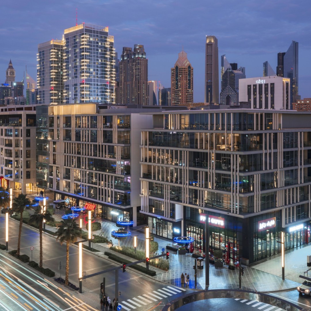 Modern illuminated Dubai retail boulevard and luxury residences at dusk
